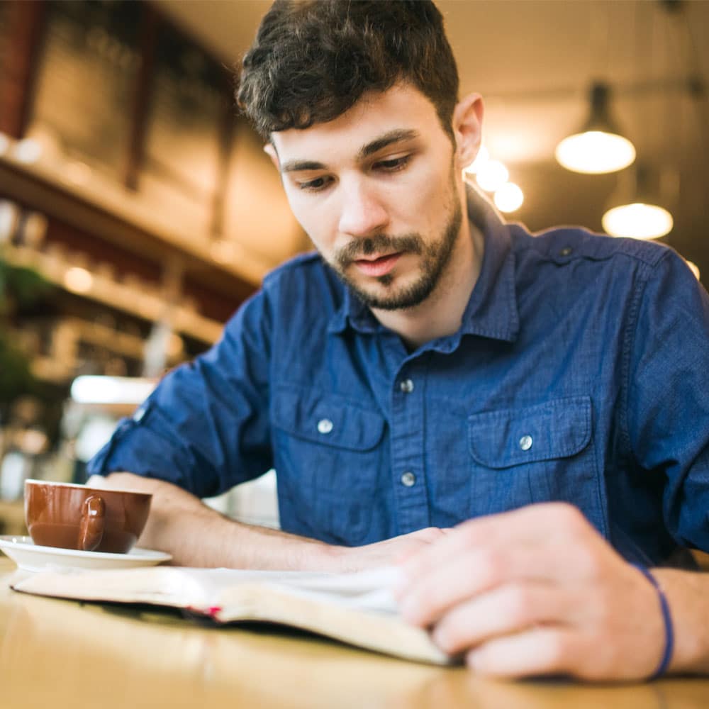 A young man studies the Bible at a coffee shop.