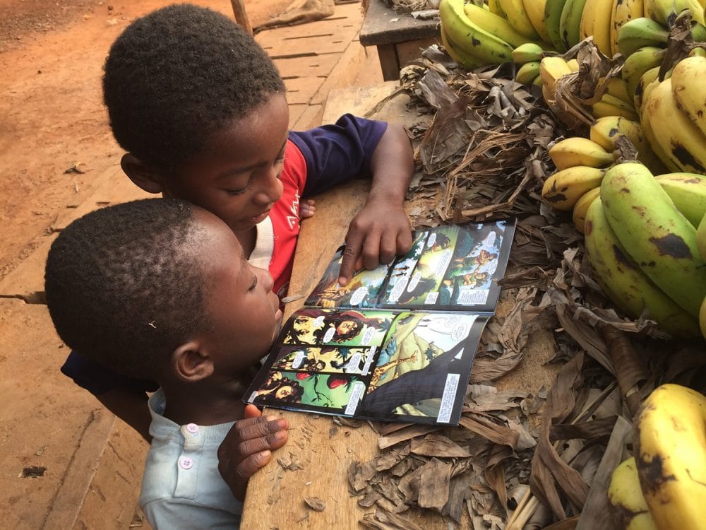 Two young boys read The Story of Jesus comic.